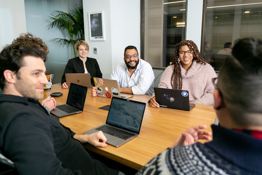 Four colleagues around a table with laptops, mid-conversation